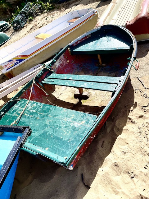 An old green rowing boat on the sand